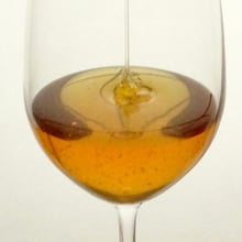 amber honey pouring into a clear wind glass