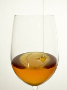 green-gold sakura honey pouring in a thin stream into a wine glass