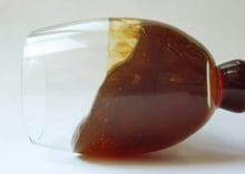A stemmed glass lying on its side with deep red-amber heather honey inside, holding its shape as a gel and full of small air bubbles.