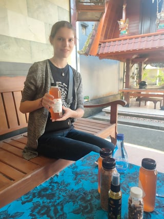 Woman holding a jar of honey, with a few jars on a table in the foreground.