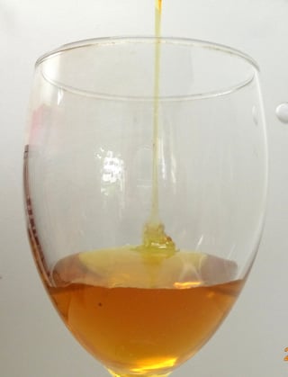 wine glass being filled with amber colored honey