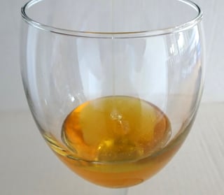 Partly filled wineglass with golden honey.
