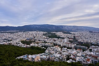A long grey-green mountain ridge rising behind a wide spread of white city buildings.