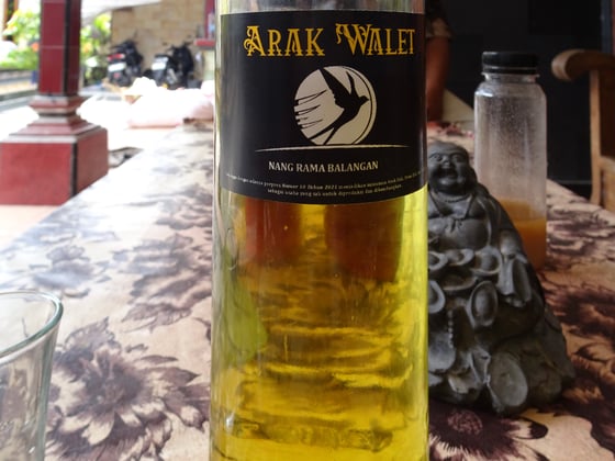 Tall bottle of yellow Arak liquor with lable on a table.
