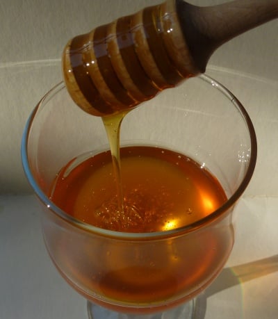Amber, transparent honey drizzling into a wineglass.