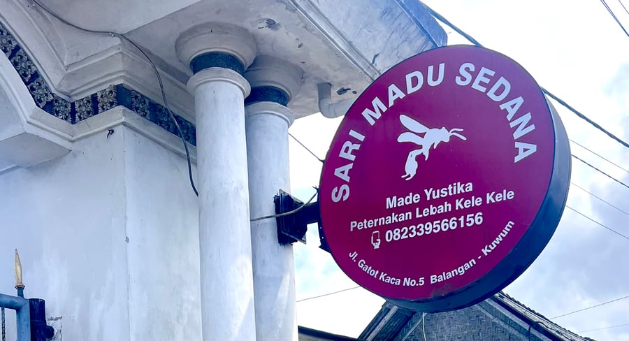 Round red sign for Sari Madu Sedana Bee Farm