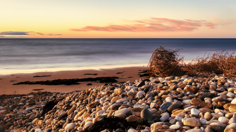 Pebble beach in the foreground of the sea.