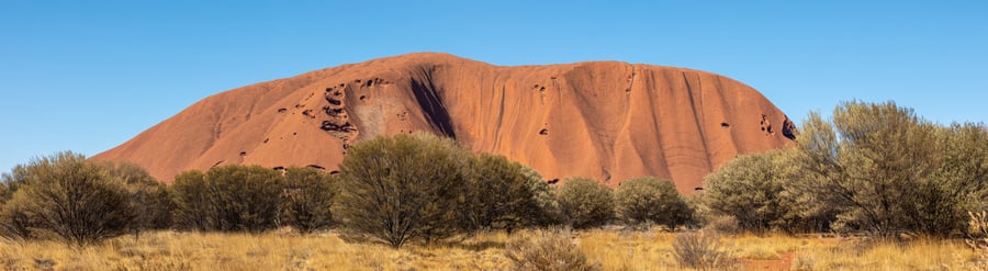 Giant red sandstone rock with trees in the foreground